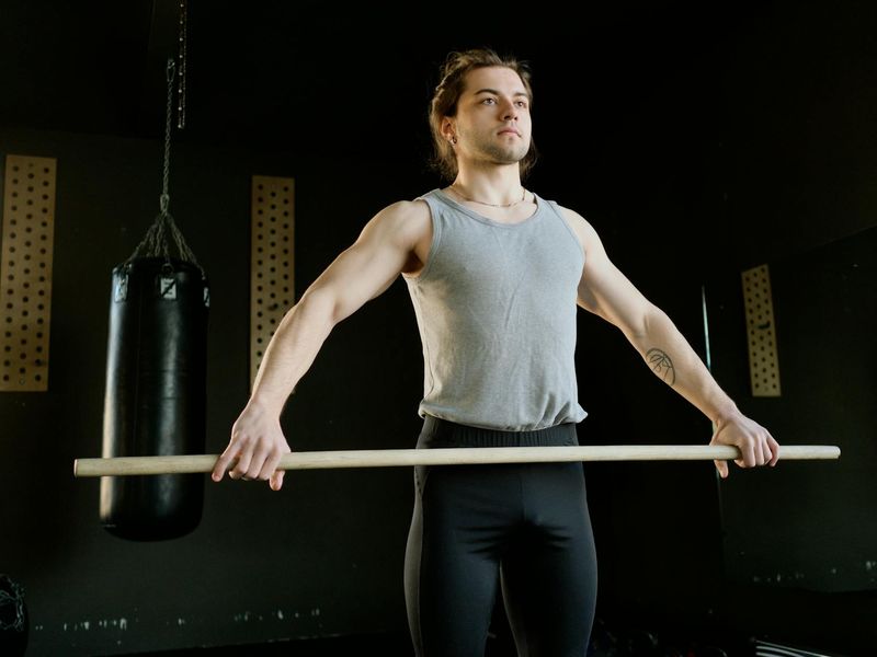 Man in a focused stance during a bodyweight exercise, with orange light highlighting his form.