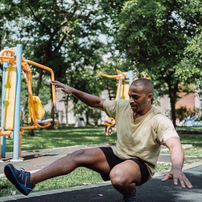 Man slowly lowering himself during a bodyweight squat exercise.