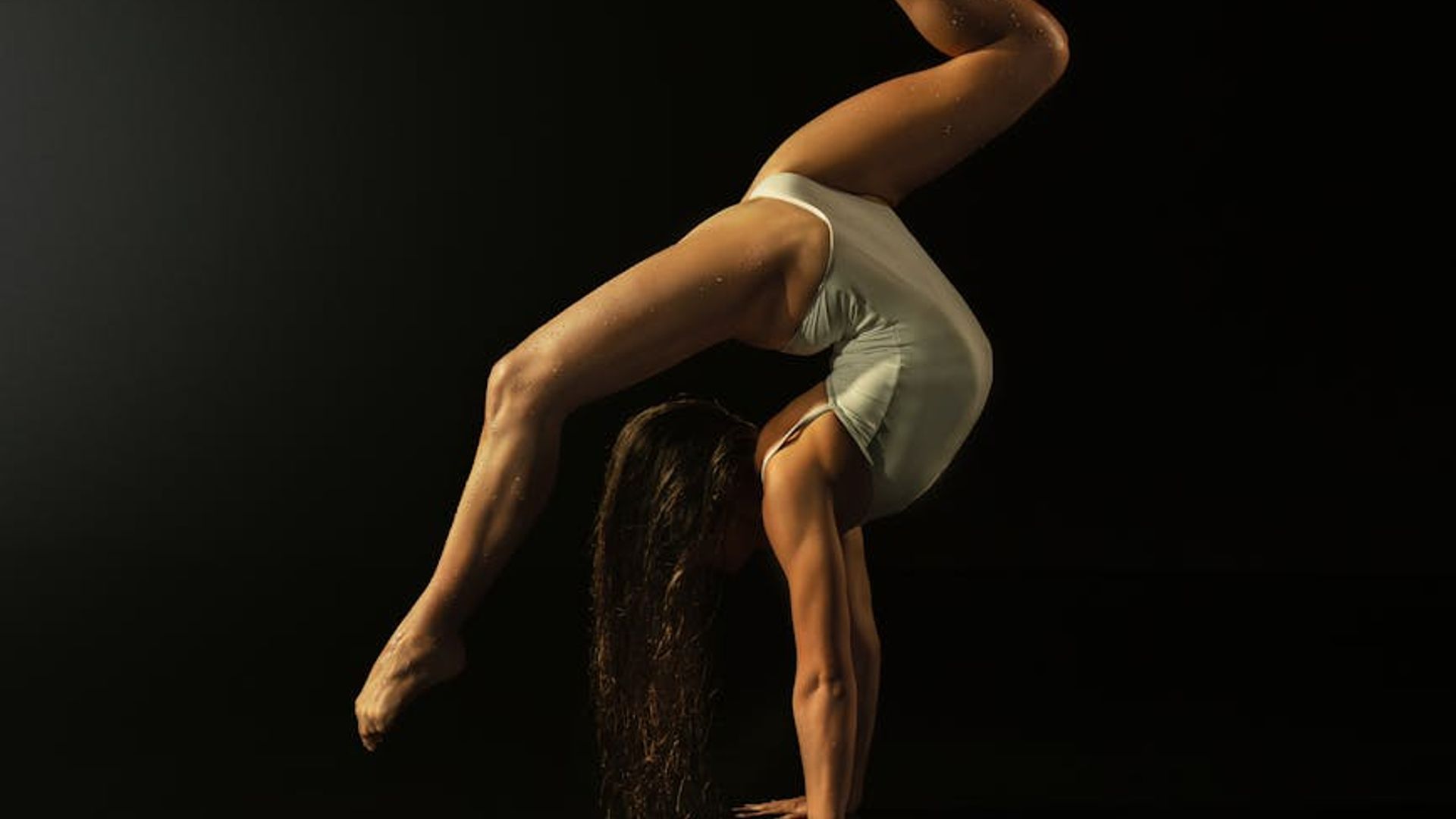 Silhouette of a man performing a controlled strength exercise in a dark room.